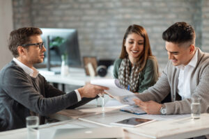 happy couple signing contract meeting with their real estate agent office